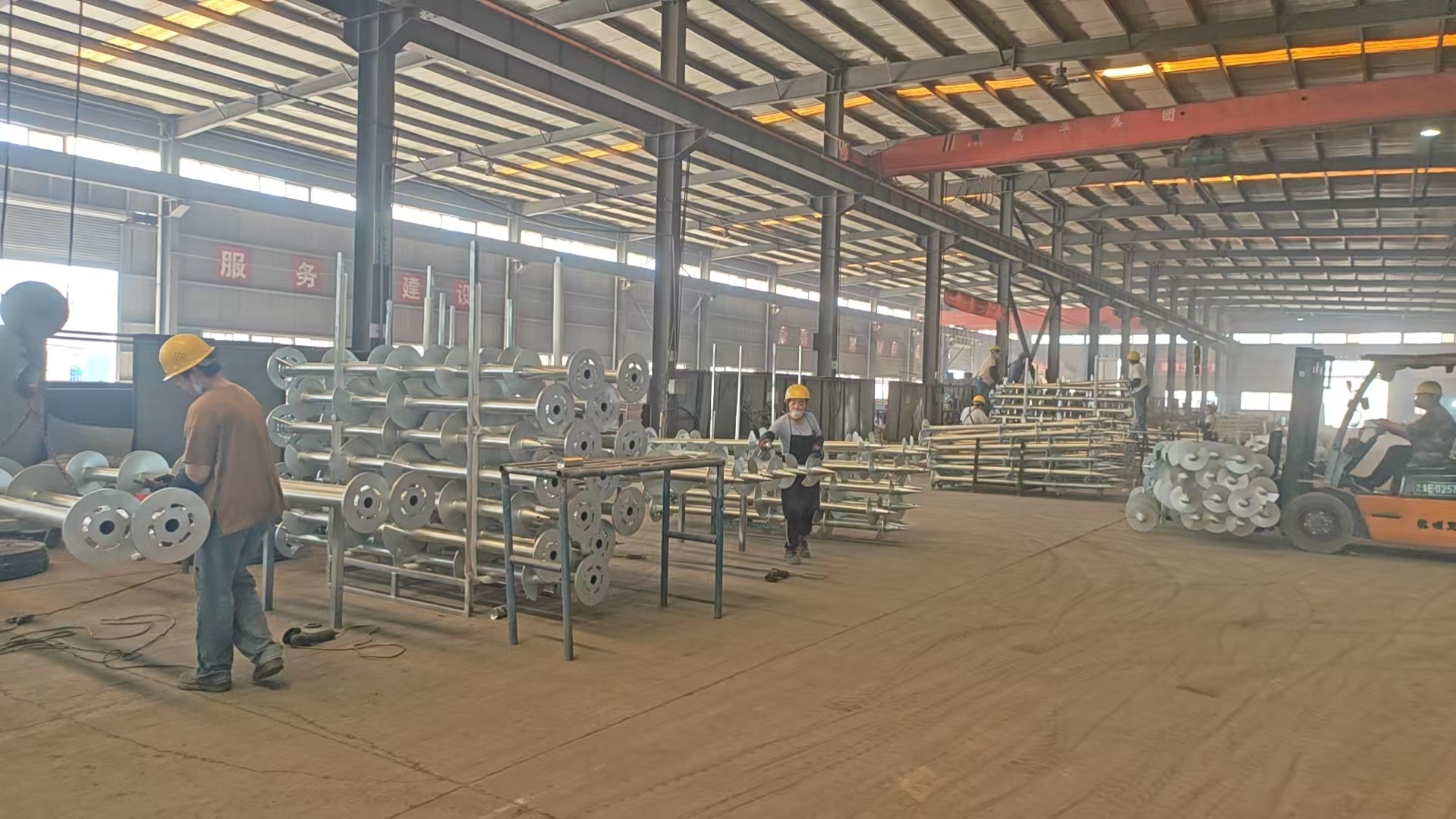 Workers producing galvanized spiral ground piles in the Leonsolar factory workshop